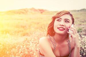 sexy beautiful woman talking on smartphone in flower field photo