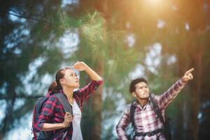 Young couple stop looking for something during hiking together. photo