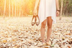 Young woman carrying shoes when she tired to walk in forest photo