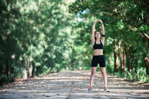 mujer joven fitness estirando las piernas antes de correr. foto