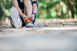 Young beautiful listening to music and tying laces on her shoe. photo