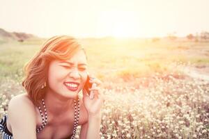 woman using a smartphone in flower field in summer laugh so happy photo