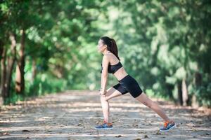 mujer joven fitness estirando las piernas antes de correr. foto