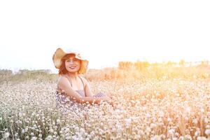 woman wearing hat sitting in flower field with fresh  in the morning photo