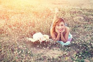 Woman resting on the flower field smiling outdoors. photo
