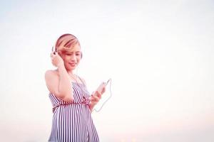 hermosa mujer sexy escuchando música desde el teléfono inteligente en la flor. foto