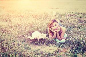 joven mujer sexy descansando en el campo de flores. sonriendo a la cámara foto