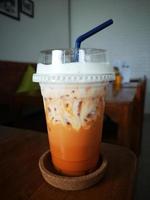 Milk ice tea in takeaway plastic cup on table in cafe, Thailand. photo