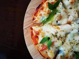 close-up pizza on wooden plate with dark brown copyspace. photo