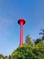 Tanque rojo de la torre de agua tailandesa con cielo azul. foto vertical.