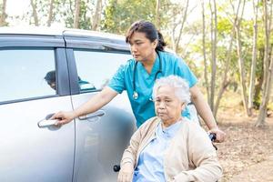 Asian senior woman patient sitting on wheelchair get to her car photo