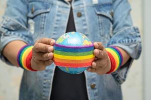 Señora asiática sosteniendo la bandera de colores del arco iris con globo, símbolo de lgbt foto