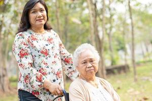 Asian senior woman patient with care on wheelchair in park photo