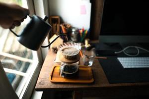 goteo de café en casa, vertiendo agua caliente sobre un goteo de café foto