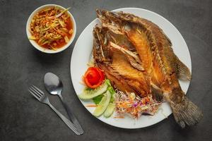 Fried snapper in a plate placed on a black background photo