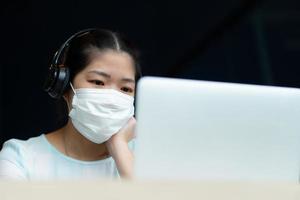 youwoman wearing mask and using computer video call conference photo