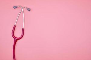 A pink stethoscope on the pink background photo