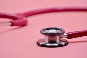 A close up pink stethoscope on the pink background photo