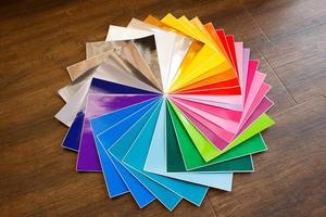 Twisted pile of colorful 12x12 sheets of adhesive paper on brown photo