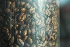 Granos de café tostados oscuros en un frasco de vidrio en el café vintage