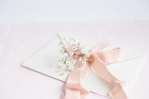 Envelope on a white-pink background with peach silk ribbon and pink photo
