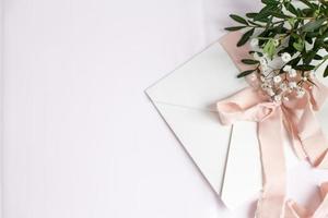 Envelope on a white-pink background with peach silk ribbon and pink photo