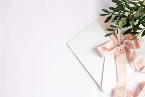 Envelope on a white-pink background with peach silk ribbon photo