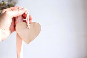 corazón de madera en cinta rosa. mano sosteniendo corazón de madera. copie el espacio.