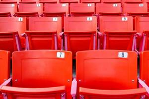 Row of red folding chairs in a stadium. photo