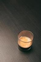 Photo of glass of coffee espresso on dark wooden table