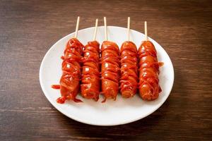 Fried sausage skewer with ketchup on white plate photo