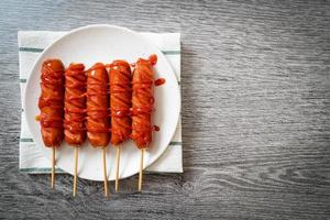 Brocheta de salchicha frita con salsa de tomate en la placa blanca. foto