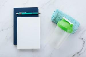 Blank white paper note and fitness equipment on marble background photo