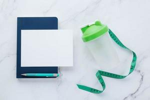 Blank white paper note and fitness equipment on marble background photo