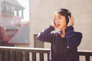 Feliz joven mujer asiática escuchando música con auriculares foto