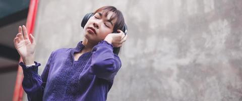 Happy young asian woman listening to music with headphones photo