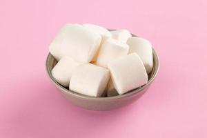 Marshmallow in bowl on pastel pink background photo