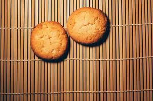 dos galletas redondas y crujientes, en bambú texturizado, diseño simple foto