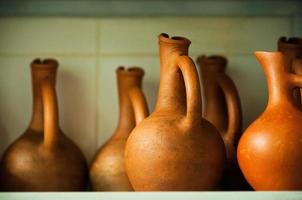 Soft focused wine jugs of terracotta color on the rack photo