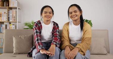 Zwillingsmädchen winken mit der Hand, während sie auf der Couch sitzen video