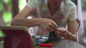 vista ravvicinata di una donna anziana che cuce il tessuto per realizzare ricami a casa video