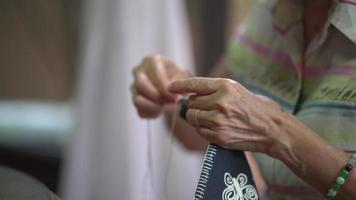 Vista de cerca de la mujer mayor de coser telas para hacer bordados en casa