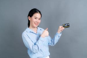 Portrait of a lovely young Asian woman showing credit card photo