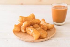 Deep-fried dough stick with milk tea on wood photo