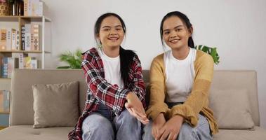 Twin Girls Waving Hand While Sitting on Couch