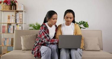 meninas gêmeas planejando trabalhar no laptop enquanto estão sentadas no sofá video