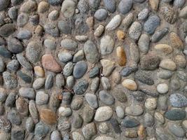 A wall built of a mixture of round pebble stones and cement photo