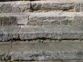 escalones de piedra frontalmente. Hierba de primavera entre losas de piedra, cerrar foto