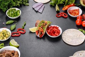 Mexican tacos with beef, tomatoes, avocado, onion and salsa sauce photo