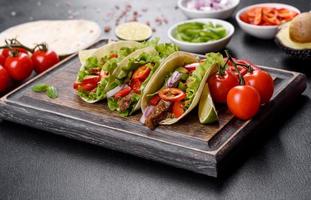 Mexican tacos with beef, tomatoes, avocado, onion and salsa sauce photo